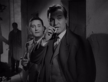 Movie still from “I Vitelloni” (1953), directed by Federico Fellini – Two men in suits and ties are smoking a cigarette; Medium shot, Low angle