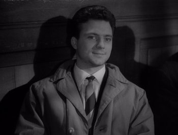 Movie still from “I Vitelloni” (1953), directed by Federico Fellini – Black and white photograph of a young man in a raincoat; Close Up shot, High angle