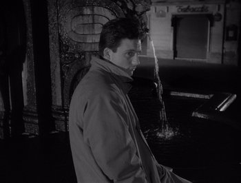 Movie still from “I Vitelloni” (1953), directed by Federico Fellini – A black and white photo of a man standing in front of a fountain; Medium shot, High angle