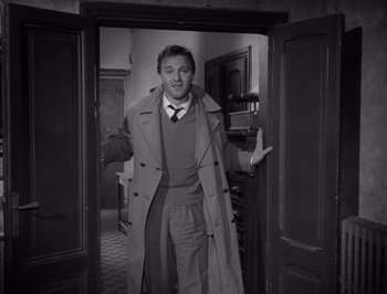 Movie still from “I Vitelloni” (1953), directed by Federico Fellini – A black and white photo of a man standing in a doorway; Medium shot, Over the shoulder angle