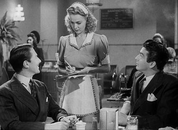 Movie still from “I Wake Up Screaming” (1941), directed by H. Bruce Humberstone – Two men and a woman sitting at a table in front of a waitress; Medium shot, Over the shoulder angle