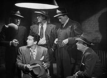 Movie still from “I Wake Up Screaming” (1941), directed by H. Bruce Humberstone – A black and white photo of a group of men in suits and hats; Medium shot, High angle