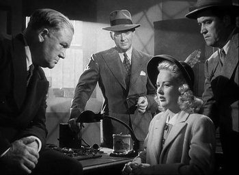 Movie still from “I Wake Up Screaming” (1941), directed by H. Bruce Humberstone – A group of people standing around a table; Medium shot, Over the shoulder angle