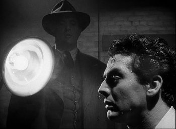 Movie still from “I Wake Up Screaming” (1941), directed by H. Bruce Humberstone – A black and white photo of a man in a hat; Close Up shot, Over the shoulder angle