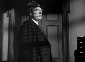 Movie still from “I Wake Up Screaming” (1941), directed by H. Bruce Humberstone – A man wearing a hat and a coat; Medium shot, Low angle