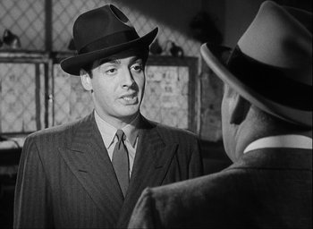 Movie still from “I Wake Up Screaming” (1941), directed by H. Bruce Humberstone – A man wearing a suit and a hat talking to another man wearing a suit and a hat; Close Up shot, Over the shoulder angle