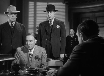 Movie still from “I Wake Up Screaming” (1941), directed by H. Bruce Humberstone – A black and white photo of a group of men in suits and hats; Medium shot, Low angle