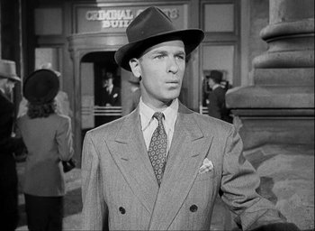 Movie still from “I Wake Up Screaming” (1941), directed by H. Bruce Humberstone – A black and white photo of a man wearing a suit and hat; Medium shot, Low angle