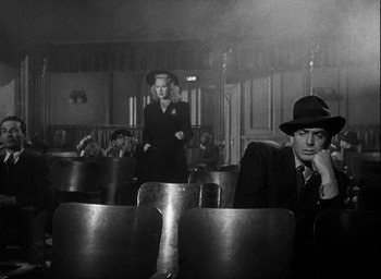 Movie still from “I Wake Up Screaming” (1941), directed by H. Bruce Humberstone – A man and a woman sitting in a theater; Wide shot, Low angle