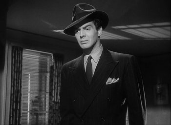 Movie still from “I Wake Up Screaming” (1941), directed by H. Bruce Humberstone – A man in a suit and hat standing in a room; Close Up shot, Low angle