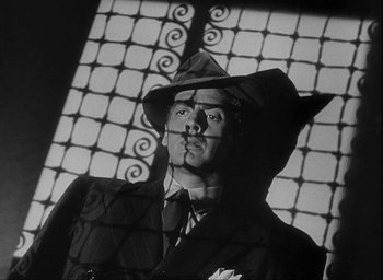 Movie still from “I Wake Up Screaming” (1941), directed by H. Bruce Humberstone – A black and white photo of a man in a suit and hat; Close Up shot, Low angle