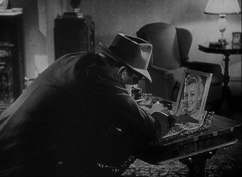 Movie still from “I Wake Up Screaming” (1941), directed by H. Bruce Humberstone – A black and white photo of a man looking at a picture of a woman; Close Up shot, High angle