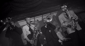 Movie still from “I Want to Live!” (1958), directed by Robert Wise – A group of men in suits playing musical instruments in a room; Medium shot, Low angle