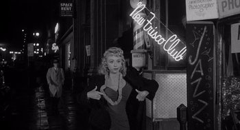 Movie still from “I Want to Live!” (1958), directed by Robert Wise – An old photo of a woman pointing to a neon sign; Medium shot, Low angle