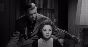 Movie still from “I Want to Live!” (1958), directed by Robert Wise – A man and a woman sitting on a couch in front of a window; Medium shot, Low angle