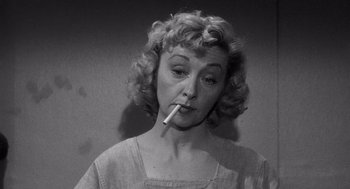 Movie still from “I Want to Live!” (1958), directed by Robert Wise – An older woman smoking a cigarette in a black and white photo; Close Up shot, Low angle