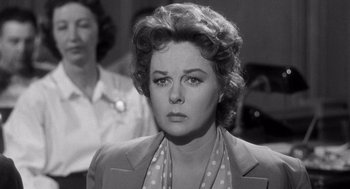 Movie still from “I Want to Live!” (1958), directed by Robert Wise – An old black and white photo of a woman in a suit; Close Up shot, Over the shoulder angle