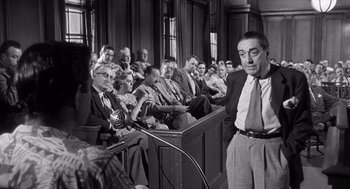 Movie still from “I Want to Live!” (1958), directed by Robert Wise – A man standing in front of a group of people in a courtroom; Medium shot, Low angle