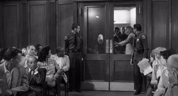 Movie still from “I Want to Live!” (1958), directed by Robert Wise – A black and white photo of a group of people in front of a building; Medium shot, Over the shoulder angle