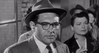 Movie still from “I Want to Live!” (1958), directed by Robert Wise – A man wearing a hat and glasses in a black and white photo; Close Up shot, Low angle