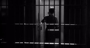 Movie still from “I Want to Live!” (1958), directed by Robert Wise – A man standing in a jail cell behind bars; Medium shot, Low angle