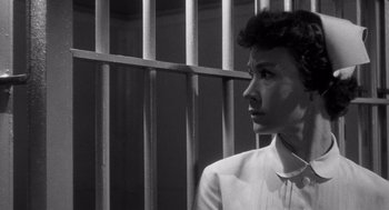 Movie still from “I Want to Live!” (1958), directed by Robert Wise – A man standing in front of a metal fence; Close Up shot, Low angle
