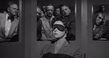 Movie still from “I Want to Live!” (1958), directed by Robert Wise – A woman with a blindfold in front of a group of men; Medium shot, Over the shoulder angle
