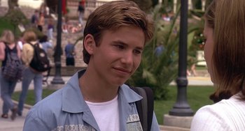 Movie still from “I'll Be Home for Christmas” (1998), directed by Arlene Sanford – A young man with a backpack standing in a park; Close Up shot, Over the shoulder angle