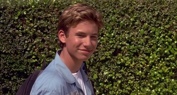 Movie still from “I'll Be Home for Christmas” (1998), directed by Arlene Sanford – A young man standing in front of a wall of bushes; Close Up shot, Low angle