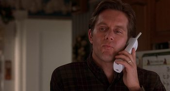 Movie still from “I'll Be Home for Christmas” (1998), directed by Arlene Sanford – A man holding a phone up to his ear; Close Up shot, Low angle