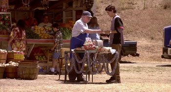 Movie still from “I'll Be Home for Christmas” (1998), directed by Arlene Sanford – A man standing next to a table of food; Wide shot, Over the shoulder angle