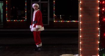 Movie still from “I'll Be Home for Christmas” (1998), directed by Arlene Sanford – A man dressed as santa claus standing on a sidewalk; Wide shot, Low angle