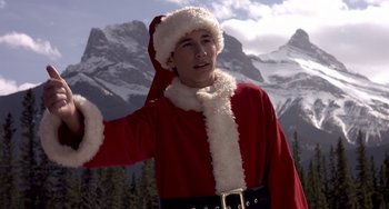 Movie still from “I'll Be Home for Christmas” (1998), directed by Arlene Sanford – A man dressed as santa clause in front of a snowy mountain; Medium shot, Low angle