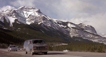 Movie still from “I'll Be Home for Christmas” (1998), directed by Arlene Sanford – A van driving down a road near a mountain range; Extreme Wide shot, High angle