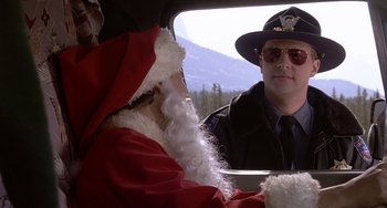 Movie still from “I'll Be Home for Christmas” (1998), directed by Arlene Sanford – A man in a police uniform sitting in the back of a car; Medium shot, Low angle