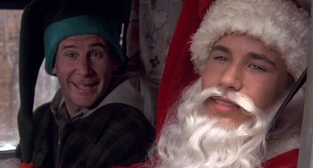 Movie still from “I'll Be Home for Christmas” (1998), directed by Arlene Sanford – A man in a santa claus suit and a man in a green hat; Close Up shot, Over the shoulder angle