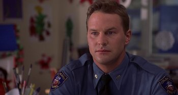 Movie still from “I'll Be Home for Christmas” (1998), directed by Arlene Sanford – A police officer is sitting in front of a window; Close Up shot, Low angle