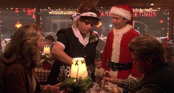 Movie still from “I'll Be Home for Christmas” (1998), directed by Arlene Sanford – A group of people standing around a table with food; Medium shot, Over the shoulder angle