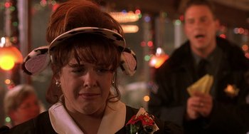 Movie still from “I'll Be Home for Christmas” (1998), directed by Arlene Sanford – A woman wearing a dress and a hat with flowers on her head; Close Up shot, Over the shoulder angle