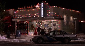 Movie still from “I'll Be Home for Christmas” (1998), directed by Arlene Sanford – A police car parked in front of a building with christmas lights on it; Extreme Wide shot, Low angle