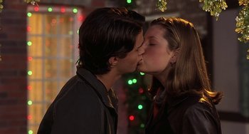 Movie still from “I'll Be Home for Christmas” (1998), directed by Arlene Sanford – Two people kissing each other in front of a christmas tree; Close Up shot, Low angle