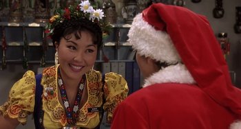 Movie still from “I'll Be Home for Christmas” (1998), directed by Arlene Sanford – A woman wearing a santa clause costume and a flower crown; Close Up shot, Over the shoulder angle