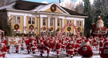 Movie still from “I'll Be Home for Christmas” (1998), directed by Arlene Sanford – A group of people dressed as santa claus in front of a building; Extreme Wide shot, High angle