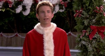 Movie still from “I'll Be Home for Christmas” (1998), directed by Arlene Sanford – A man in a santa clause outfit standing in front of a christmas tree; Close Up shot, Over the shoulder angle