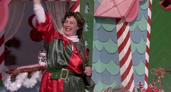 Movie still from “I'll Be Home for Christmas” (1998), directed by Arlene Sanford – A woman dressed as a christmas elf holding an umbrella; Medium shot, Low angle