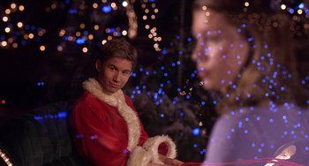 Movie still from “I'll Be Home for Christmas” (1998), directed by Arlene Sanford – A young boy dressed as santa claus sitting in front of a christmas tree; Close Up shot, Over the shoulder angle