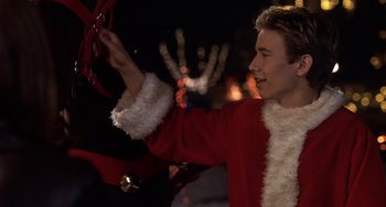 Movie still from “I'll Be Home for Christmas” (1998), directed by Arlene Sanford – A man in a santa clause suit holding a red ribbon; Close Up shot, Low angle