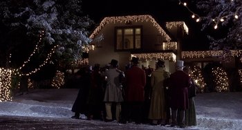 Movie still from “I'll Be Home for Christmas” (1998), directed by Arlene Sanford – A group of people standing in front of a house at night; Extreme Wide shot, Low angle