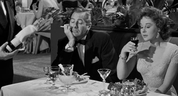 Movie still from “I'll Cry Tomorrow” (1955), directed by Daniel Mann – A black and white photo of a man sitting at a table with a cigarette in his mouth; Medium shot, High angle