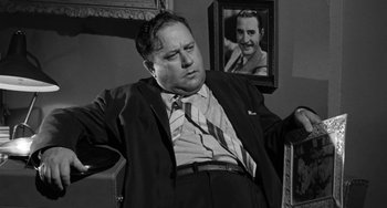 Movie still from “I'll Cry Tomorrow” (1955), directed by Daniel Mann – A man in a suit sitting in front of a picture of himself; Medium shot, Low angle